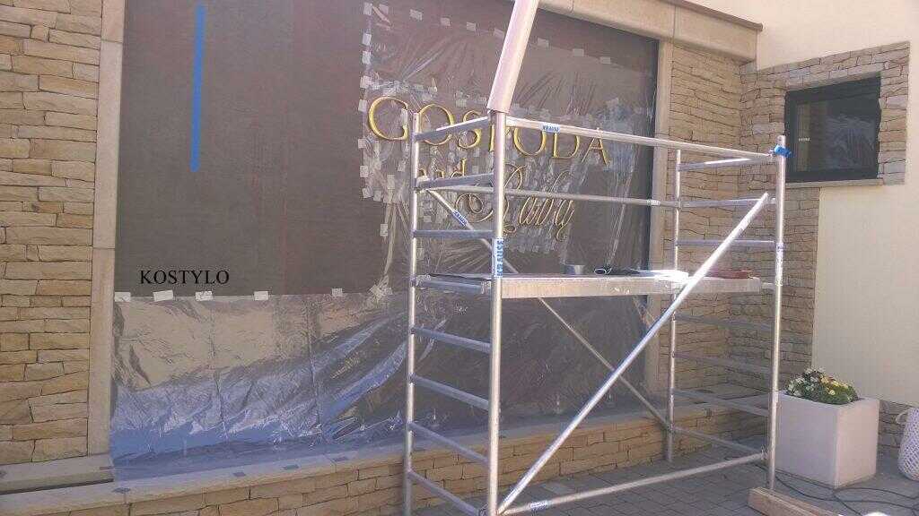 installation on brown stone wall, handcrafted by Kostylo atelier of company's openwork bas-relief along with designer letters made from polished brass
