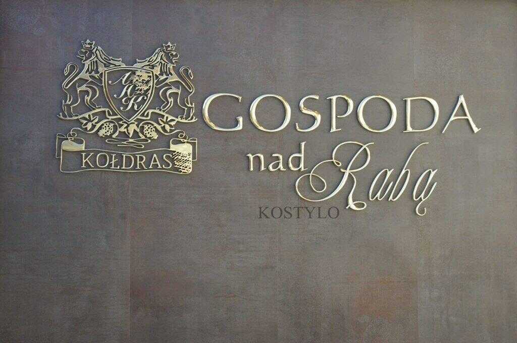 luxurious openwork bas-relief made of high-gloss polished brass depicting company logo in the shape of crest with two eagles wearing crowns along with lettering in an interesting design and style handcrafted by Kostylo atelier