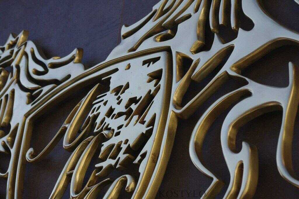 close-up of luxury brass openwork company bas-relief in the shape of logo and crest, hand-polished to high gloss in Kostylo atelier