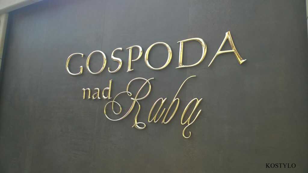 large luxurious brass letters with an interesting design polished to high gloss mounted on wall of brown stone by Kostylo atelier