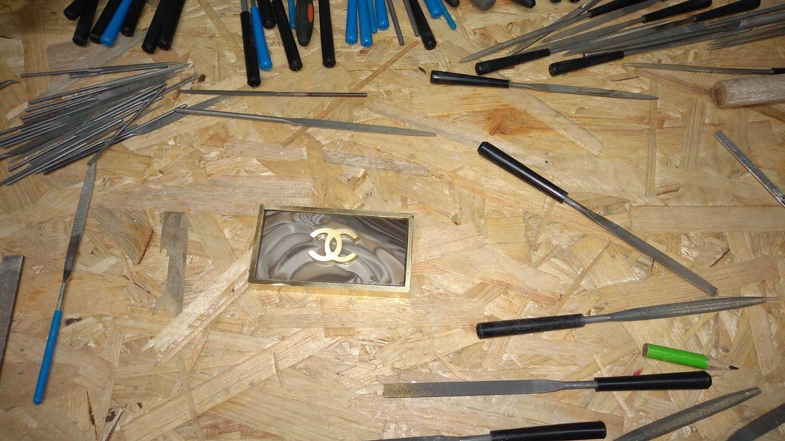 belt buckle that is hand-grinded, featuring carefully fitted unique rare striped flint and the coco chanel logo authored by Kostylo atelier before being copper-plated and gilded