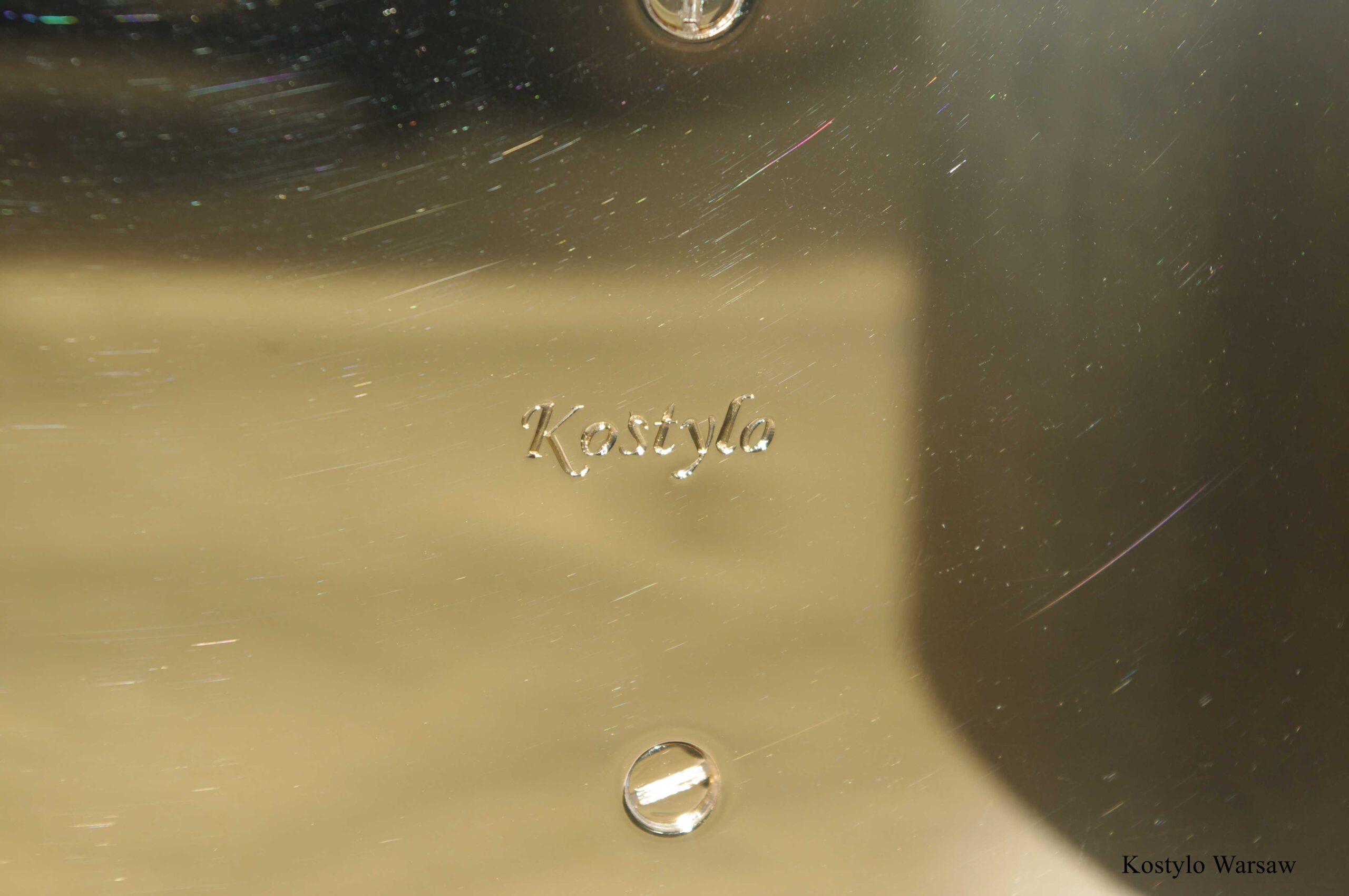 huge_luxurious_gold_plated_buckle_for_an_luxury_dress_with_original_design_butterfly_authored_kostylo_atelier View from the back of a massive gold buckle for a luxury skirt with the Kostylo logo hand-engraved on it. Also visible are gold-plated screws that, with watchmaker precision, secure the sculpture of the luxury butterfly at the front handcrafted by kostylo atelier