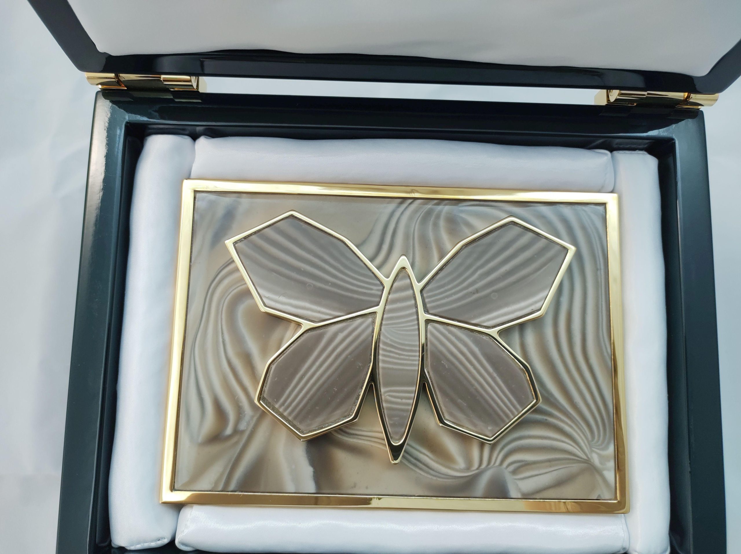 luxurious_gold_plated_buckle_with_huge_sculpture_gilded_butterfly_with_unique_striped_flint_stone_all_handmade_by_kostylo_atelier A top view inside the branded dark green box lined with soft satin, showcasing the luxurious buckle plated with Italian gold, featuring beautiful sculpture of large butterfly adorned with rare striped flint, all handmade at Kostylo atelier