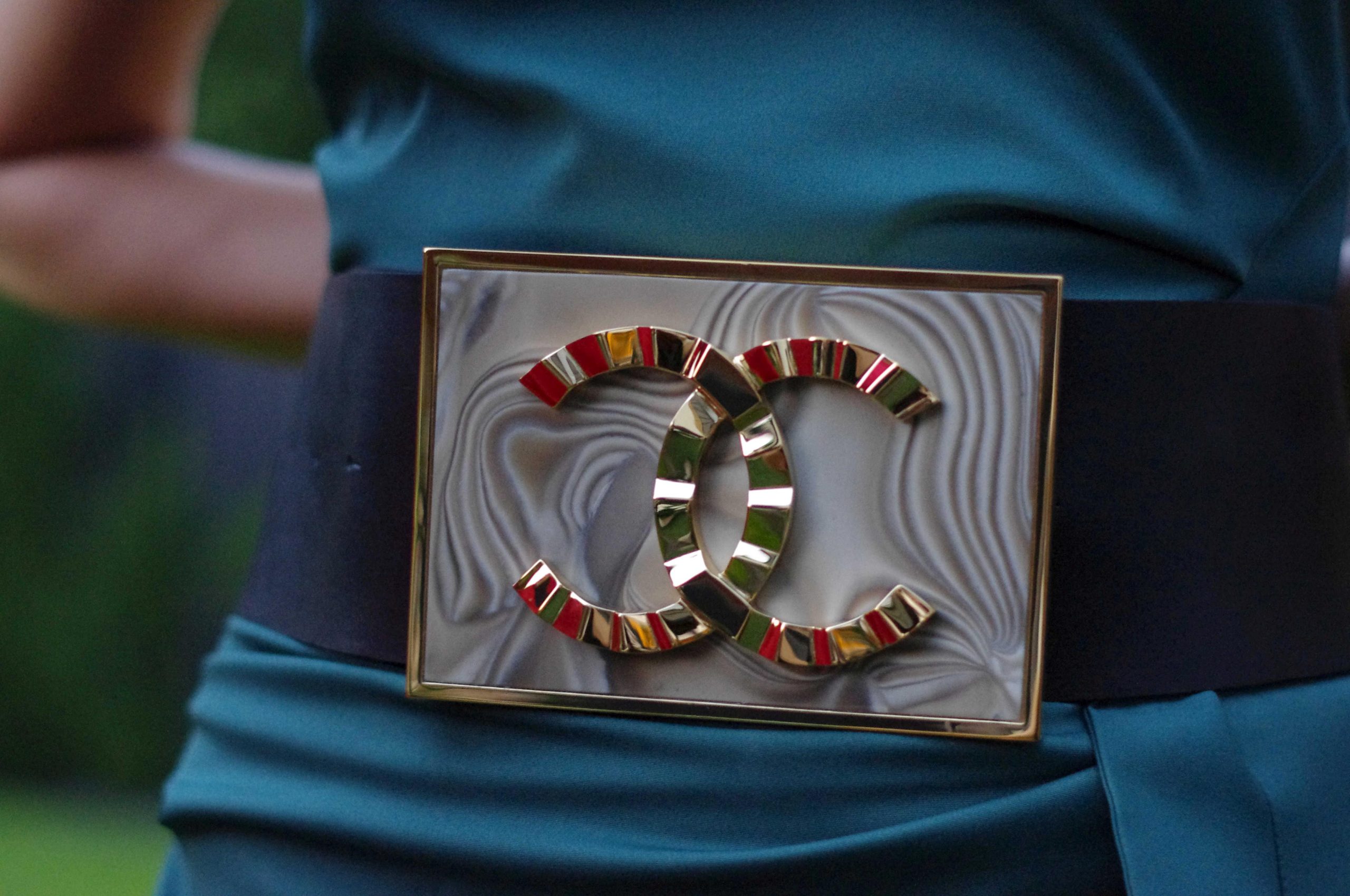 luxurious_gold_plated_italian_gold_buckle_for_luxury_dress_handcrafted_by_kostylo_atelier The unique luxury gold-plated buckle, crafted with 23 karat gold and featuring the Coco Chanel logo, beautifully complements woman in blue dress handcrafted by atelier Kostylo