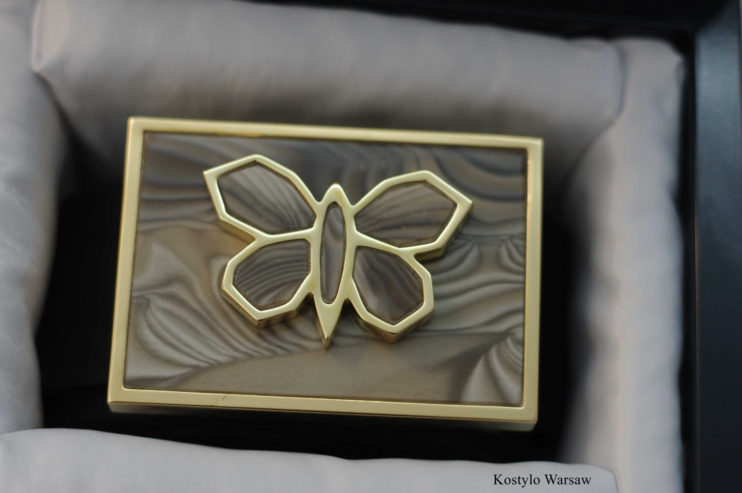 rare_original_handmade_gilded_belt_buckle_authored_kostylo_atelier View of a luxury belt buckle, gilded with pure gold in a modern style, featuring an original gold-plated butterfly figurine in banded flint stone, presented in the brand's luxury handmade box crafted by the Kostylo atelier