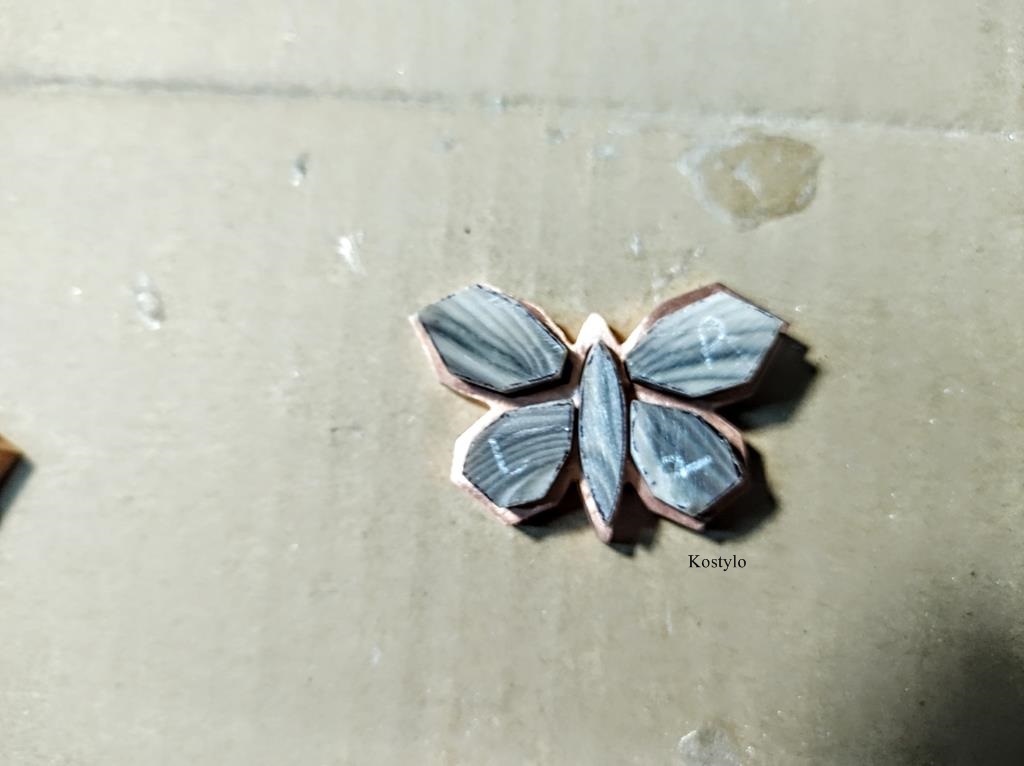 Precisely fitting pieces of semi-precious striped flint stone to the butterfly bas-relief by Kostylo atelier